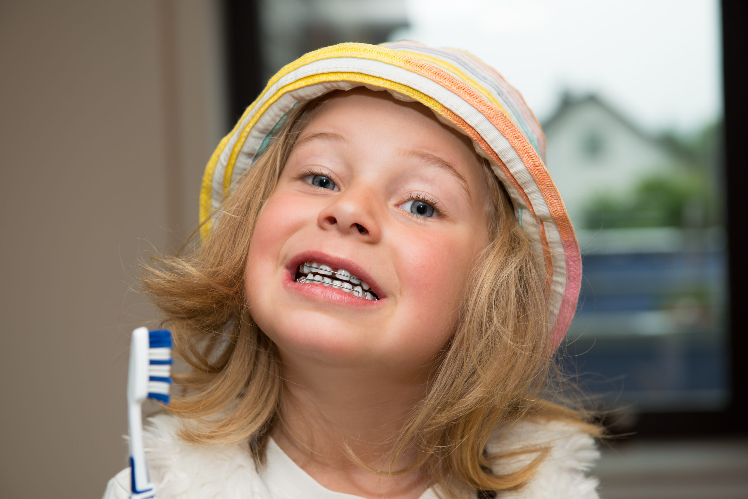 little funny girl with retainer and toothbrush looking in to the camera