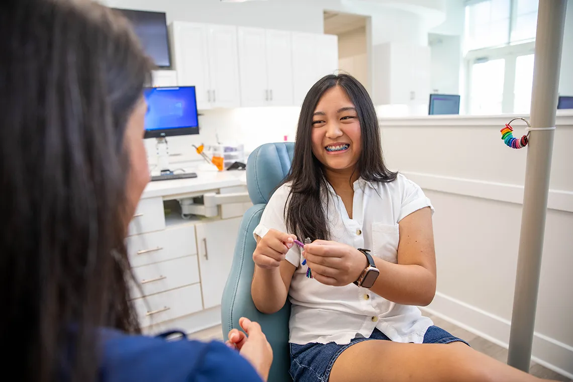 girl with braces speaking to dental tech