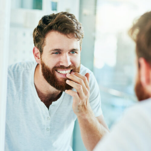 Cropped shot of a handsome young man looking at his teeth in the bathroom mirror