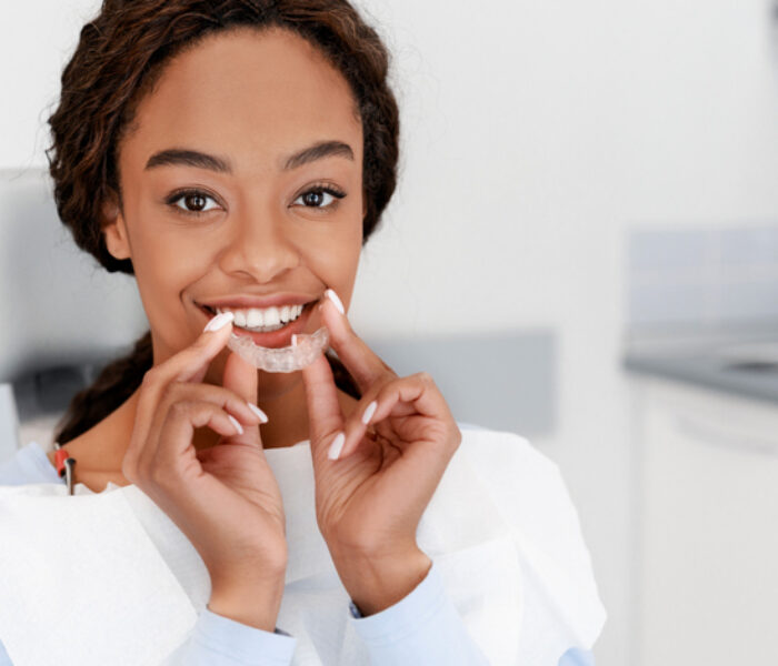 Dental Treatment Concept. Close up of young black woman holding invisible aligner, whitening tray, free space