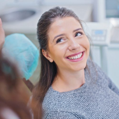 Happy woman having her teeth examined at dentist office. Female dentist performing dental examination on woman.
